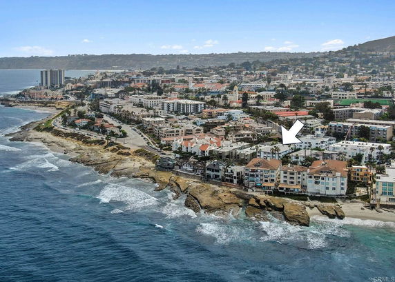 Aerial view of a coastal city with numerous buildings along the shoreline and an ocean view.