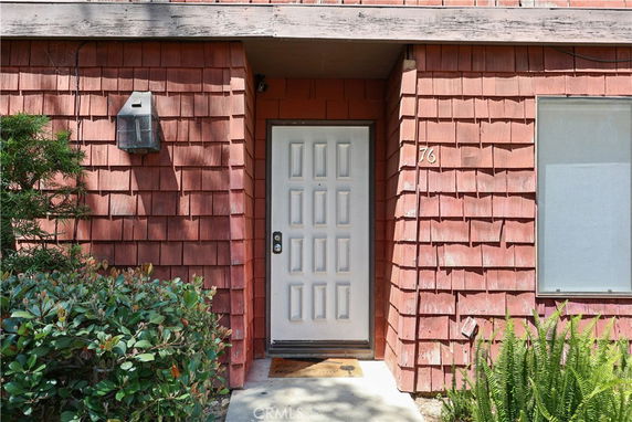 Front view of a house with a wooden shingle exterior and a white door.
