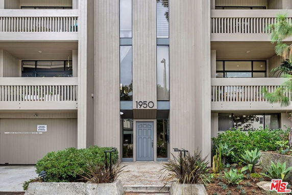 Front view of a multi-story building with balconies and vertical siding.