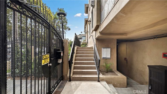 Staircase leading to an elevated entry of a building, with metal fencing on the side.