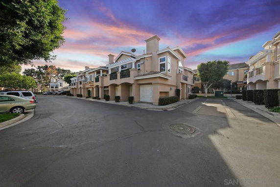 Front view of a row of two-story townhouses with garages in a residential area.