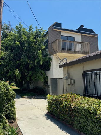 Front view of a two-story house with a balcony and a side walkway.