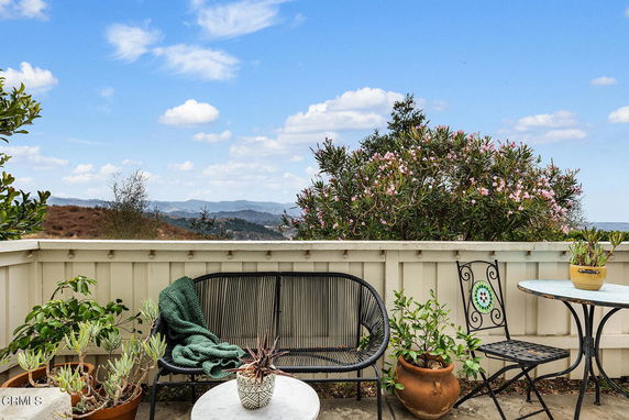 Outdoor patio with seating area and view of distant hills and greenery.