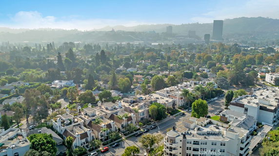 Wide angle view of a residential area with various buildings and distant hills.