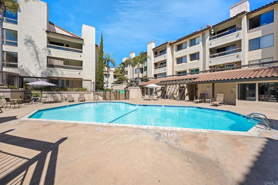 Outdoor swimming pool with multi-story building in the background.