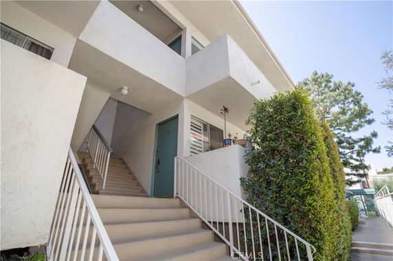 Front view of a two-story building with a staircase and greenery.