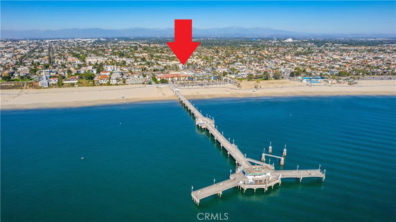 Wide angle view of buildings and coastline with a pier extending into the water.