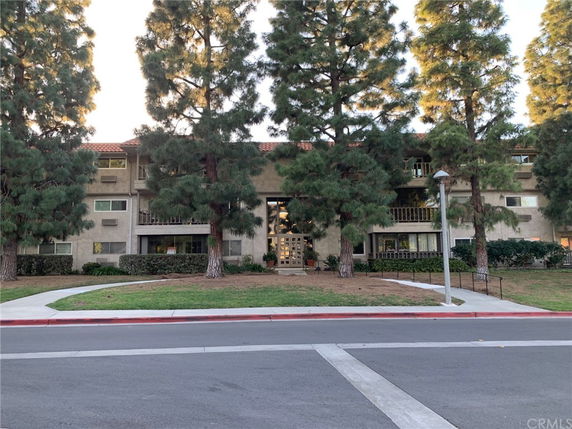Front view of a multi-story residential building with balconies and a tiled roof.