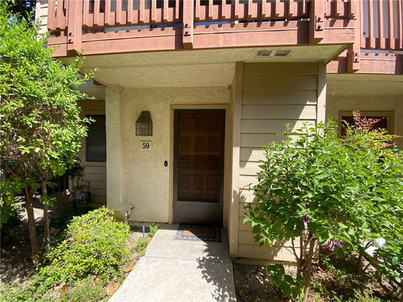 Front view of a house entrance with a wooden balcony above.