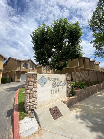Front view of a multi-story residential building with a name sign in front.