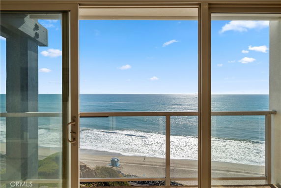 Ocean view from a building with a glass balcony railing overlooking the beach.
