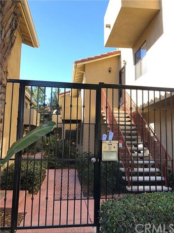 Front view of a multi-story residential building with a gated entry and stairs leading to the upper floors.