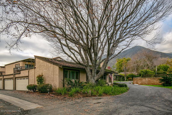 Front view of a house with a three-car garage and large tree in front.