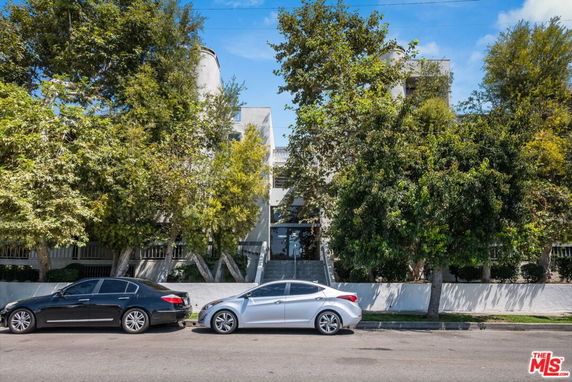 Front view of a multi-story building partially obscured by trees.