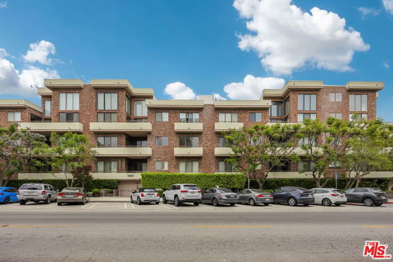 Front view of a multi-story apartment building with brick facade and balconies.