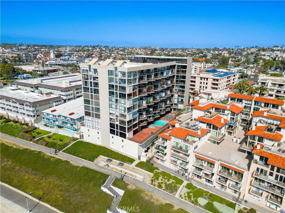 Aerial view of a tall apartment building with balconies, surrounded by other residential structures.