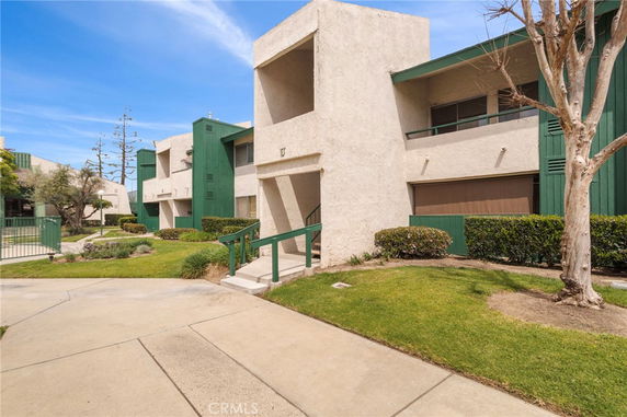 Front view of an apartment complex with green accents and a central entrance.