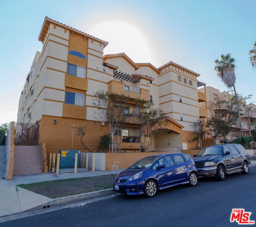 Front view of a multi-story apartment building with a stucco exterior and a flat roof.