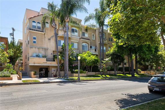 Front view of a multi-story residential building with palm trees in front.