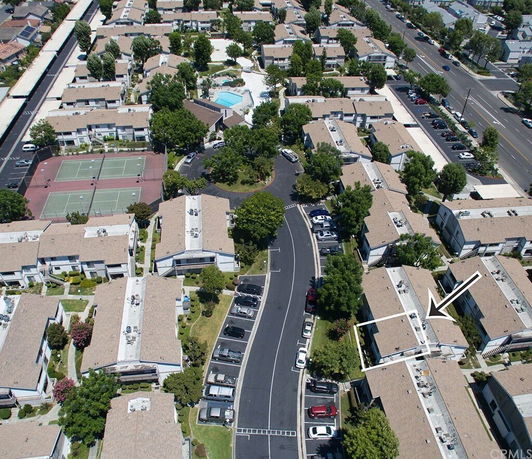 Aerial view of a complex with multiple residential buildings, tennis courts, and a swimming pool.