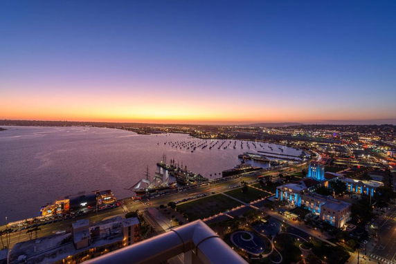 Panoramic view of a waterfront cityscape at sunset with buildings and boats.