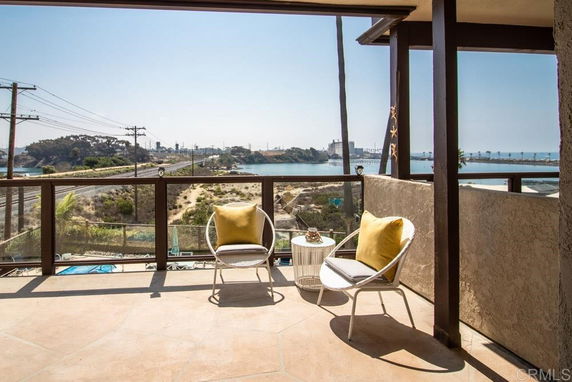 Balcony with chairs overlooking a scenic view of water and landscape.