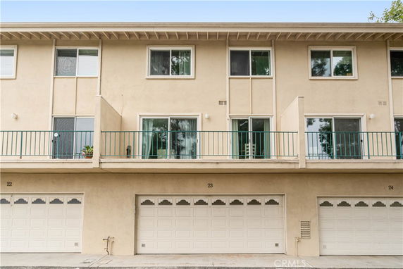 Front view of a multi-story building with balconies and garages.