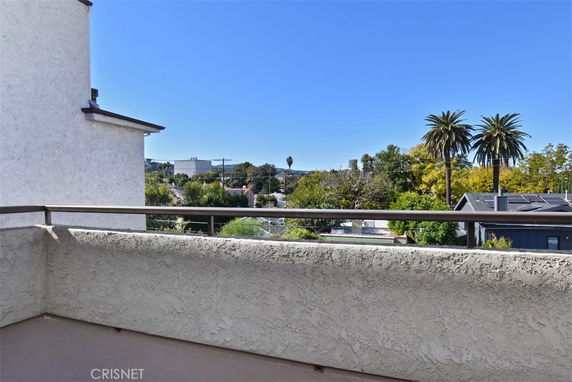 View from a balcony overlooking a suburban area with trees and buildings.