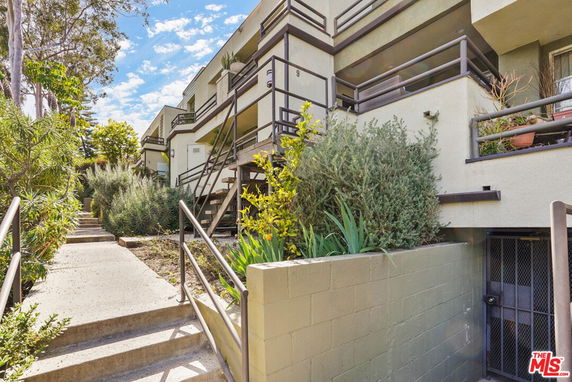 Front view of a multi-story residential building with balconies and stairway.
