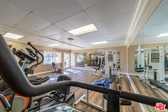 Interior gym area with exercise equipment and mirrors on the wall.