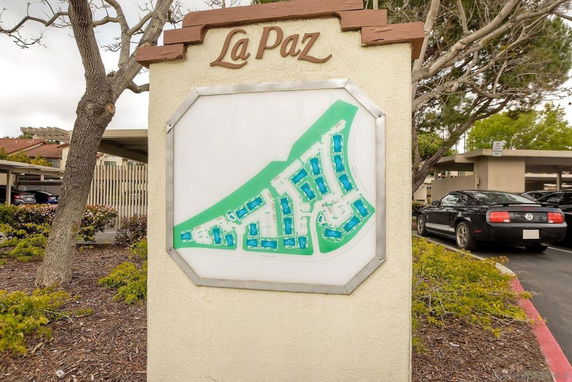 Outdoor view showing a map display at the entrance of a residential area named 'La Paz' with parked cars and buildings in the background.