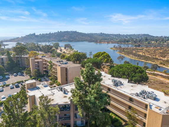 Wide-angle view of buildings and surrounding landscape with a water body and hills in the background.