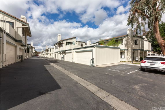 View of a row of two-story houses with attached garages facing a paved alley.
