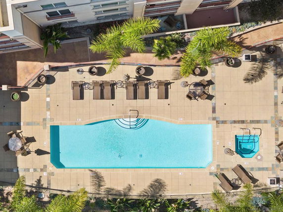 Top view of an outdoor swimming pool with surrounding lounge chairs and tables.