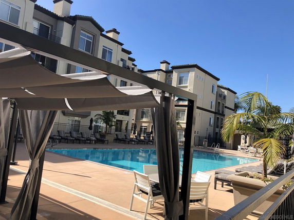 Outdoor swimming pool area with modern multi-story residential building in the background.