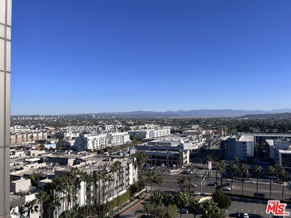 Panoramic view of city buildings with mountains in the distance.
