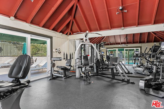 Indoor gym area with various exercise equipment and large windows.