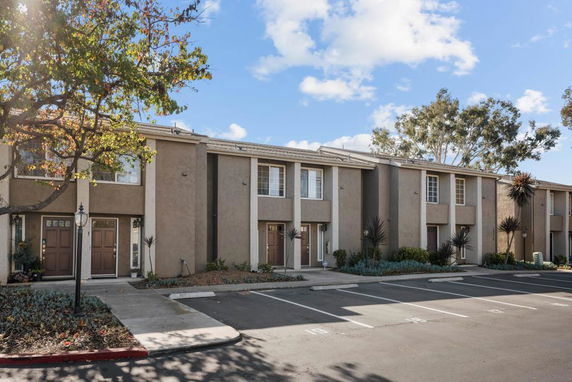 Front view of a row of two-story townhouses with parking spaces in front.