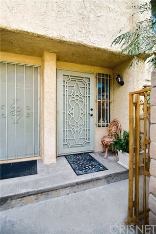Front view of a house entrance with a decorative metal door and adjacent window.