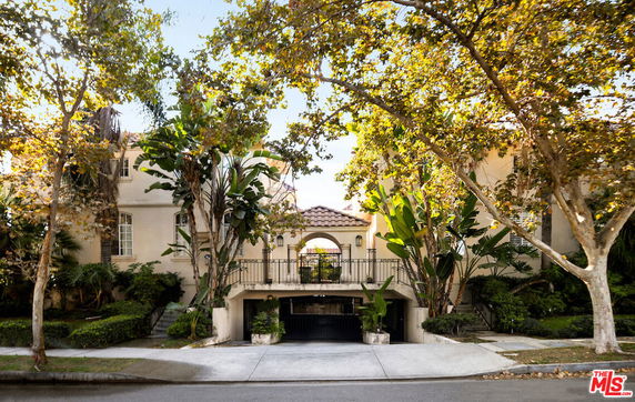 Front view of a multi-story house with a central entrance and lush greenery.