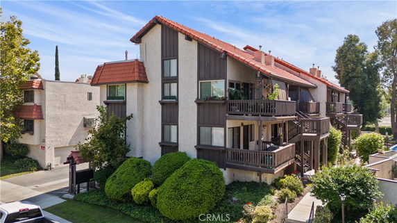 Front view of a multi-story residential building with balconies and red-tiled roofs.