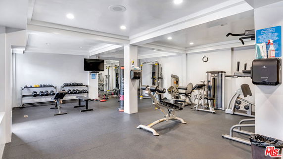Indoor gym area with various exercise equipment, including weights and machines.