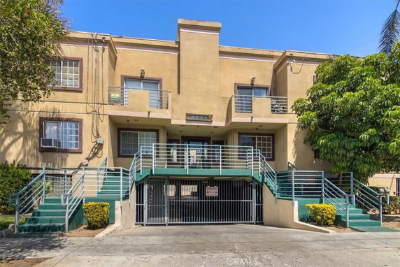 Front view of a multi-story building with balconies and an entrance staircase.