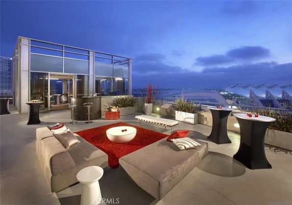 Stylish rooftop with seating arrangements and plants, overlooking a cityscape.