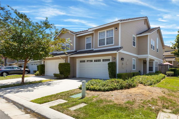 Front view of a two-story house with double garage doors and beige siding.