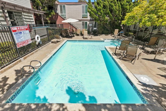 Outdoor swimming pool area with lounge chairs and surrounding fence.