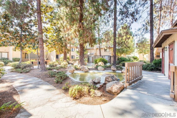 Outdoor view of a residential area with trees, footpaths, and a small pond.