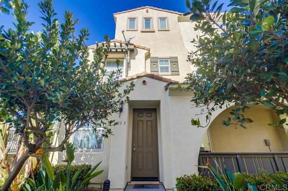 Front view of a multi-story house with beige exterior and arched entrance.