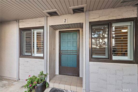 Front view of a house entrance with a teal door and adjacent windows.