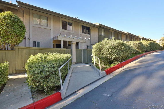 Front view of a two-story townhouse with a walkway and shrubbery.